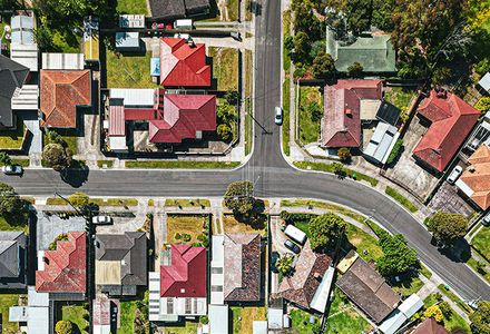 Overhead perspective of a suburban area featuring homes, roads, and landscaped gardens.