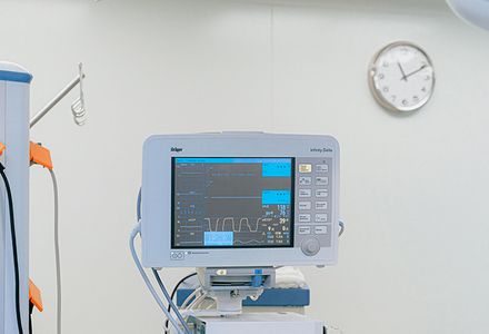 A hospital room featuring a patient bed and a medical monitor displaying vital signs.