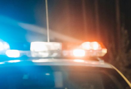 A police car displays its lights at night, casting a glow in the dark surroundings.