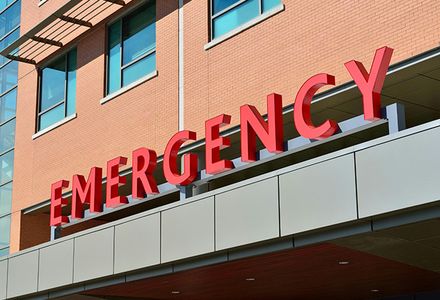 A prominent red emergency sign on a hospital's exterior wall.