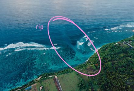 An aerial view of a rip current at a beach, with a pink circle indicating exactly where the rip can be seen.