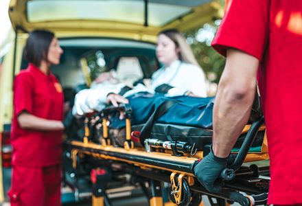 A man is being transported on a stretcher by paramedics into an ambulance.