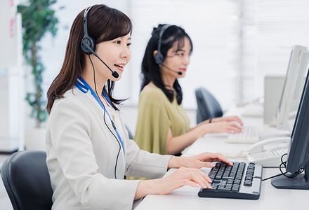 Two women wearing headsets are interpreting a phone call in a professional work environment.