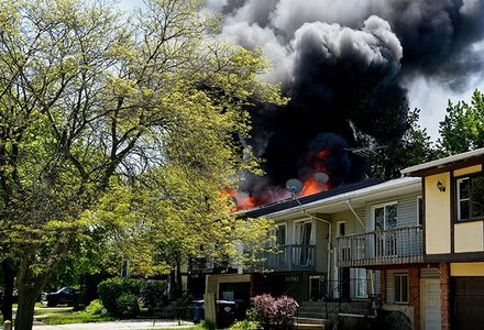 A large fire engulfs homes in a residential area, with flames and smoke rising into the sky.
